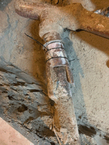 A closer look at the makeshift repair — wood and zip ties standing in for a proper plumbing fix.