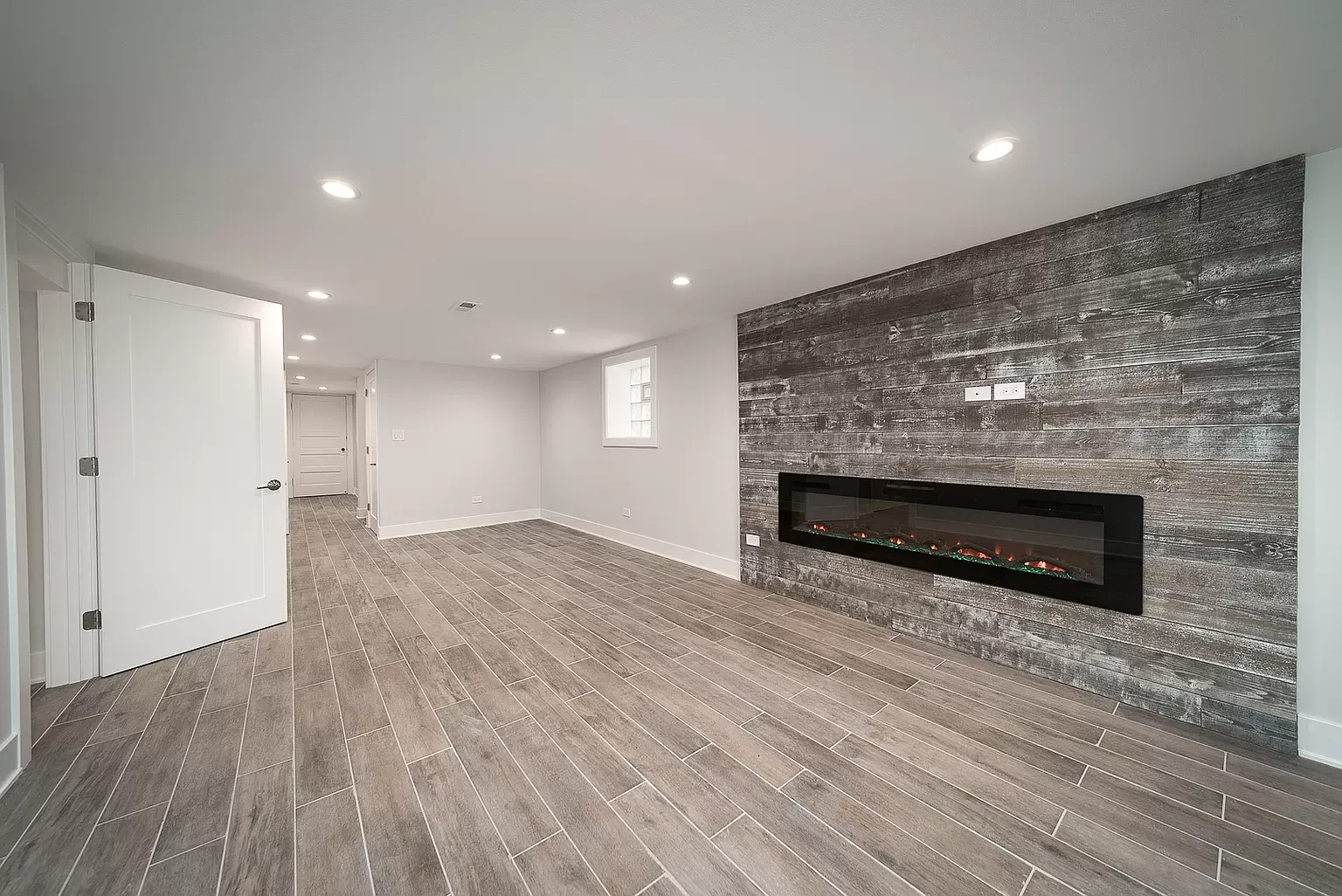 Basement renovation with a fireplace feature wall and gray tile flooring in a modern design."