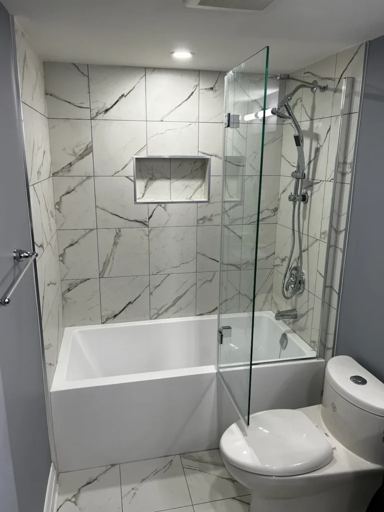 Bathroom renovation featuring a marble-tiled shower with a bathtub and modern fixture